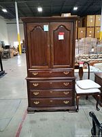 Full view of closed armoire showing doors, drawers, hardware, and overall condition