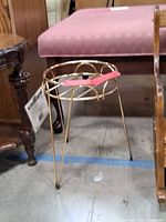 Overall view of gold-tone metal plant stand next to furniture