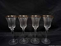 Front view of all four Mikasa gold-rim wine glasses
