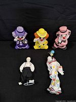 Group shot of all five clown figurines on black background
