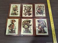 Front view of all six plaques showing lithograph images and wood finish with ruler for scale