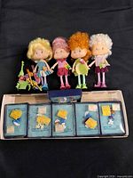 Group shot of four dolls with accessories and six boxed pins