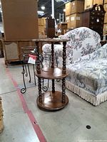 Full view of wooden round three-tier shelf standing on floor