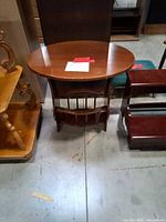 Front view of wooden oval magazine table beside other furniture