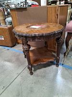 Full view of wooden side table showing scalloped top, legs, lower shelf