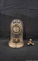 Clock with glass dome and detached pendulum shown