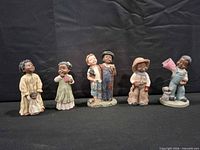 All five figurines lined up on dark backdrop