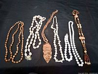 Six necklaces laid out on black background
