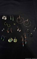 All eleven earring pairs laid out on black background
