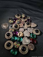 Spread of all buttons and charm on black fabric