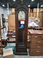 Full view of tall grandfather clock in warehouse setting