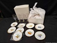 Full lot view showing boxed plates, four glasses, several plates still wrapped