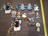 Front view of all 16 wooden and fabric ornaments laid out with ruler for scale