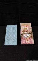 Doll in open original box alongside lid