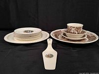 Stack of ivory scenic plates beside brown transferware stack and matching server