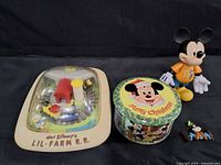 Group shot of four Disney items: Lil' Farm R.R. playset, Mickey tin, Mickey figure, Goofy figurine