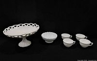 group shot of all milk glass pieces: cake stand, bowl, four teacups