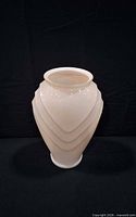 Front view of opaque peach glass vase showing tiered chevron ribs