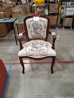 Front view of carved wood armchair with tapestry upholstery