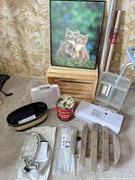 Group shot of all items including vacuum sealer, faucet packaging, wood crate, framed cat print, storage boxes, tin, basket, trivet, zip ties
