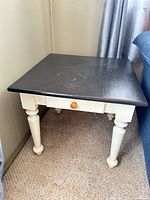 Full view of end table showing black top, white base, drawer and legs
