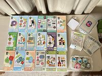 Overall view of 18 Cricut cartridge cases laid out with accessories at right