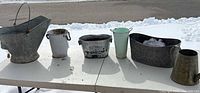 Overall view of six metal garden containers on table outdoors