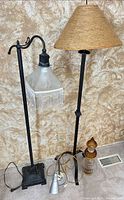 Two black floor lamps, silver task lamp base and cords visible, decorative glass finial parts on right