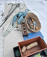 overview of lot on table showing heron stake, stakes, tools, basket, pots, planter, kneeler