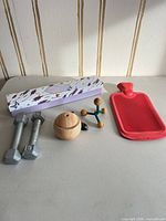 All items together: pair of dumbbells, red hot water bottle, wood-grain diffuser, boxed drawer liners, wooden massager