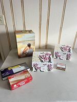 All six items laid out on table: beach scene trunk, two tulip boxes, Hilroy envelope box, Studio Post envelope pack, Chat Pack game