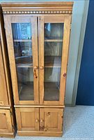 Front view showing full cabinet with glass doors and lower storage