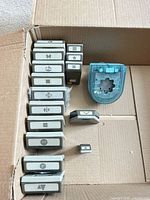 Box containing 15 grey Stampin' Up punches and one teal punch showing various shape icons
