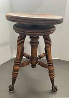 Full view of wooden piano stool showing legs and claw feet