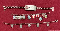 Three bracelets laid out on red background showing overall forms and charms