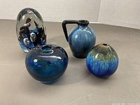 Four blue art glass pieces including paperweight, Isle of Wight vase and two additional vases