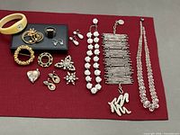 All jewelry items laid on red cloth showing quantity and variety
