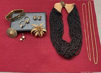 All items arranged on red background showing necklace, bracelet, brooches, rings, earrings