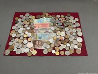 Overall view of collection spread on red felt showing quantity and variety of coins and banknotes