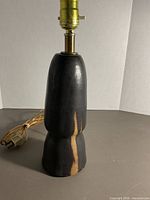 Front view of dark matte pottery lamp with tan streak, cord visible