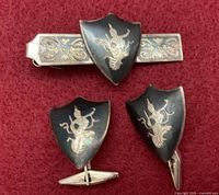 Front view of tie bar and cufflinks on red background