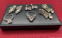Overall view of two rings and three pairs screw-back rhinestone earrings on display pad