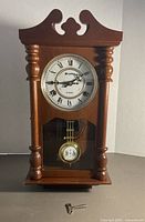 Front view of Carillon wall clock showing dial, pendulum and key