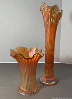Tall and small marigold carnival glass vases side by side