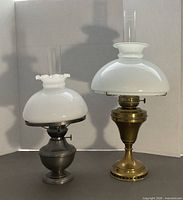 Pewter and brass oil lamps side by side showing full view with chimneys and shades