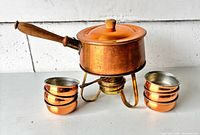 Overall view of copper fondue pot on stand with four bowls