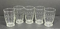 Front view of five etched glass tumblers