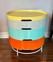 Front view showing four coloured compartments stacked on white metal base