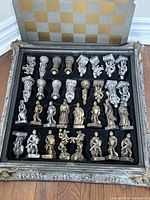 Open box showing rows of gold and silver knight chess pieces in foam insert