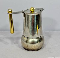 Front view of stainless espresso maker with gold handle and knob